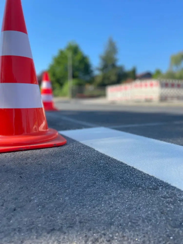 Detailansicht Thermomarkierung und Pylonen auf einer Straße